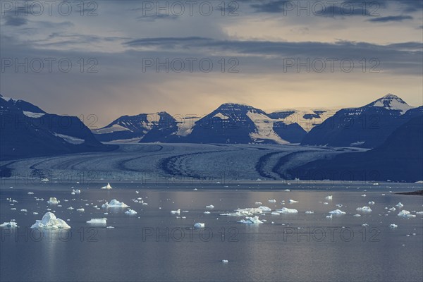 Evening mood with clouds over a glacier, glacier tongue, fjord with icebergs in front of mountains, autumn, Scoresby Sund, East Greenland, Greenland, North America