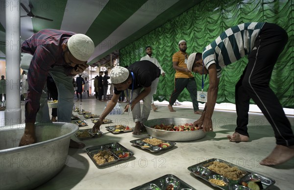 Volunteers distribute and arrange rows of 'iftar' meal for devotees to break their fast, during the holy month of Ramadan, at Burha Jame Masjid, on March 13, 2024 in Guwahati, Assam, India, Asia