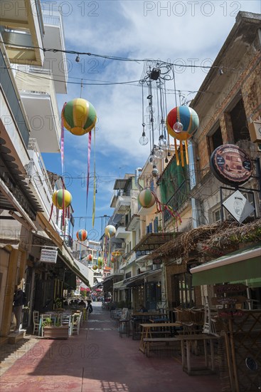 Narrow alley decorated with colourful hanging balloons, surrounded by shops, Kalamata, Messinia, Peloponnese, Greece, Europe