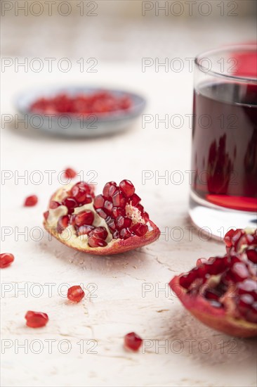 Glass of pomegranate juice on a white concrete background with red textile. Side view, close up, selective focus