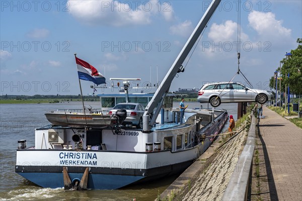 Inland waterway transport, a bargeman's vehicle is loaded from the shore onto the cargo ship with an on-board crane, Ruhrort harbour, Duisburg, North Rhine-Westphalia, Germany, Europe