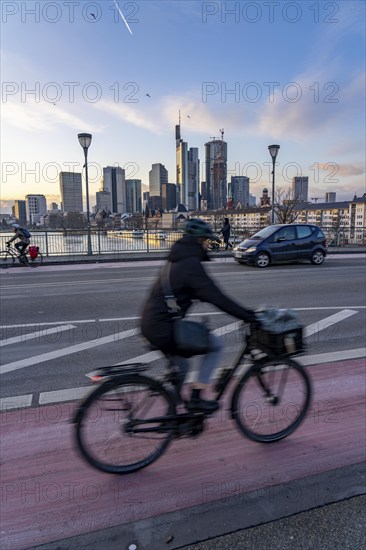 Skyline of the city centre of Frankfurt am Main, cyclist on the Ignatz-Bubis-Bridge, dusk, river Main, winter, Hesse, Germany, Europe