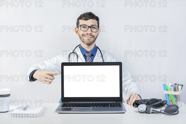 Smiling doctor pointing at an advertisement on the laptop screen. Handsome doctor pointing at an advertisement on the laptop screen
