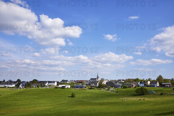 Landscape with meadows and shadows of clouds under a blue sky with cumulus clouds and a long shot of Kliding, Eifel, district of Cochem-Zell, Rhineland-Palatinate, Germany, Europe