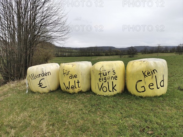 Billions of euros for the world, no money for our own people, farmers protest on bales of grass wrapped in foil against the waste of taxpayers' money by the German government