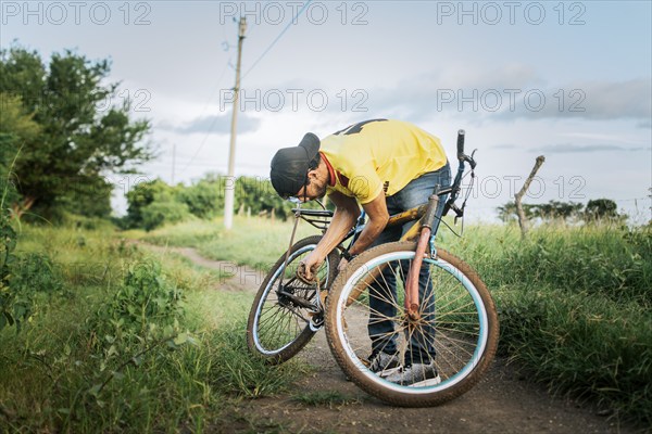 Man in the countryside repairing his bike. Person repairing his bike on the road, Man repairing his bike in the middle of the road