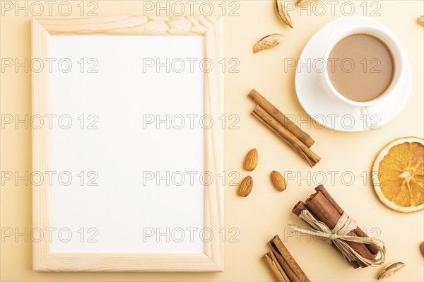 Composition with wooden frame, almonds, cinnamon and cup of coffee. mockup on orange background. Blank, flat lay, top view, still life, copy space