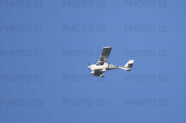 Flight Design CT2K small aircraft flying across a blue sky, England, United Kingdom, Europe