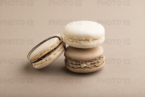 Brown and white macaroons on beige pastel background. side view, close up, still life. Breakfast, morning, concept