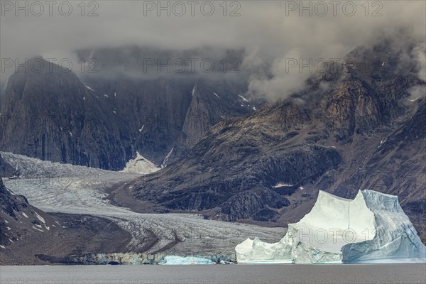 Large icebergs in fjord in front of steep mountains, glacier tongue, cloudy mood, summer, Scoresby Sound, East Greenland, Greenland, North America