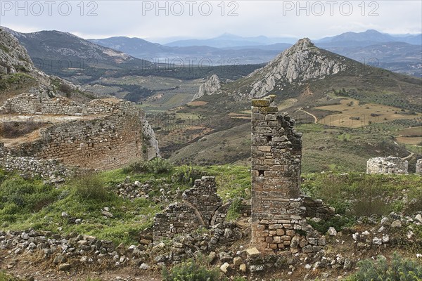 View of crumbling stone walls and ruins in a hilly landscape under a cloudy sky, Archaic Castle, Akrokorinthos, Corinth, Peloponnese, Greece, Europe