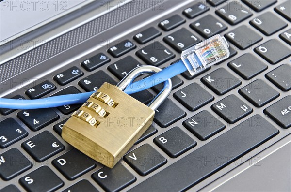 Internet cable and padlock on computer keyboard symbolizing data security