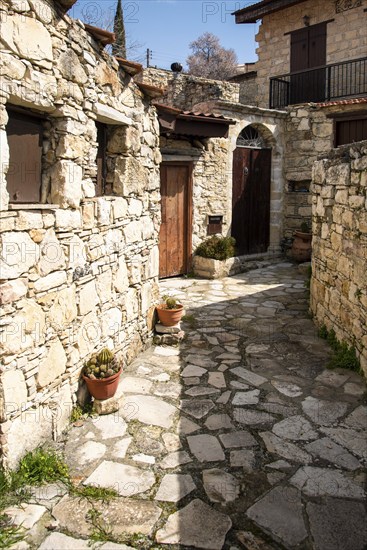 Stoned footpath crossing a traditional village. Stoned houses with wooden doors. Vintage architecture. Lofou village, Cyprus, Europe