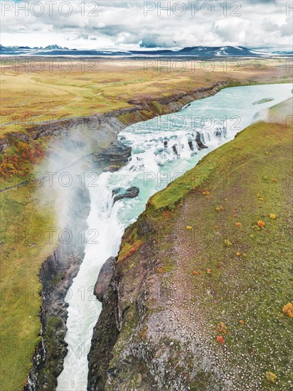 Huge beautiful waterfall Gullfoss, famous landmark in Iceland. River foaming whilst falling down the waterfall, tourist waling by, looking at the waterfall from a view point.