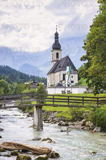 Parish church of St Sebastian by a river in an idyllic Alpine landscape with mountains and forests in the background, bridge, Ramsau, Berchtesgadener Land, Upper Bavaria, Bavaria, Germany, Europe