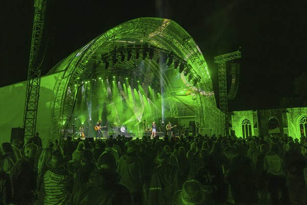 Large crowd at a night-time concert in front of a green-lit stage, Klostersommer, Calw Hirsau, Black Forest, Germany, Europe