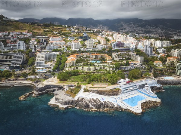 Aerial drone view of Funchal city with hotels resorts and swimming pool along the coast of Atlantic ocean. Funchal, Madeira, Portugal, Europe