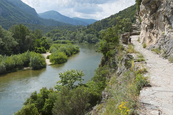A rocky hiking trail along the bank of a river with surrounding mountain views, River Nestos or Mesta, Nestos Gorge, Galani, Macedonia and Thrace, Greece, Europe