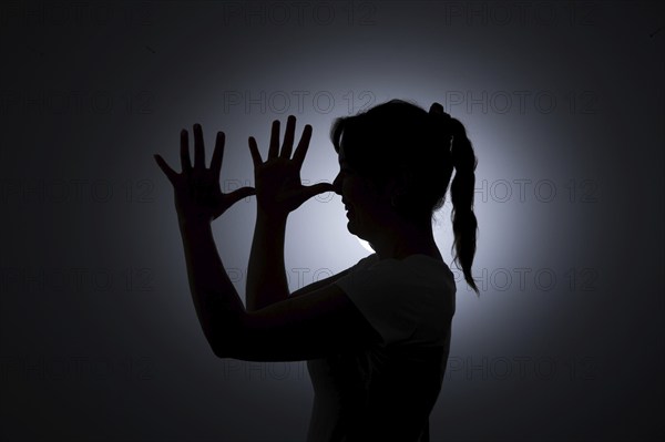 Symbol photo on the subject of being tricked. A young woman holds her hands in front of her face. Berlin, 22.08.2024
