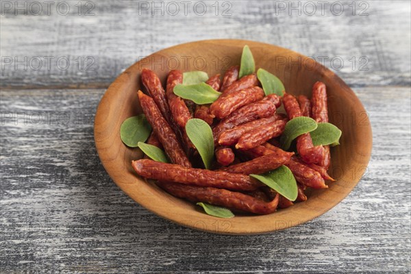 Small smoked sausage with borage microgreen, salt and pepper on gray wooden background. Side view, close up