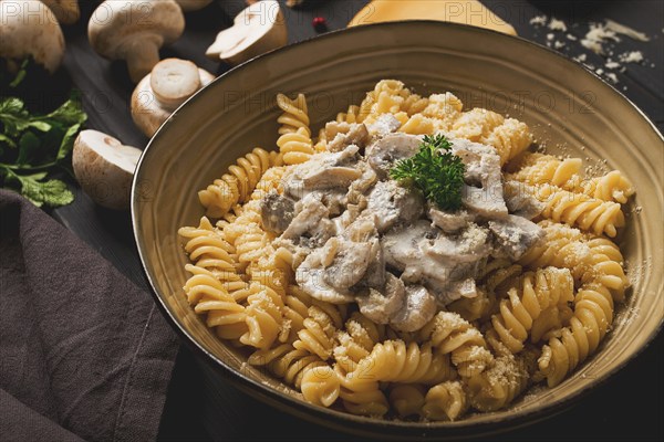 Fusilli pasta, with champignons in cream sauce, top view, with ingredients, on a wooden table, no people