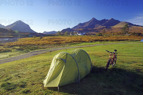 A tent and a bicycle stand on a green meadow with mountains in the background, ideal for camping, October, Slichigan, Cullins, Hebrides, Isle of Skye, Hebrides, Scotland, United Kingdom, Europe