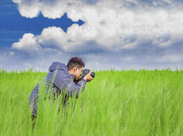 Man taking picture with camera in the field, photographer in the field taking a picture, Latino man in a green field taking a picture