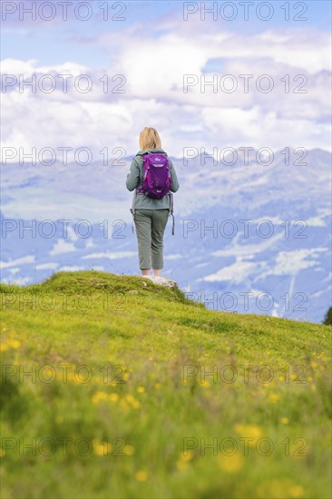 Person with rucksack looking into a wide mountain landscape, standing on a green meadow, Penken, Zillertal, Austria, Europe