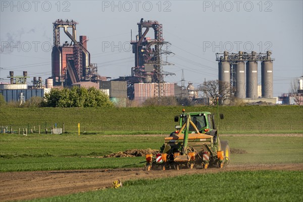 Farmer working in the field, Duisburg-Baerl, sowing, in the background the ThyssenKrupp Steel blast furnace, Duisburg, North Rhine-Westphalia, Germany, Europe