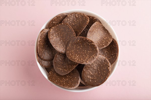 Chocolate chips with caramel on pink pastel background. top view, flat lay, close up