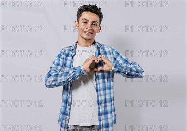 Smiling guy making heart shape with hands isolated. Happy man making heart shape with hands isolated. Person putting hands together in a heart shape