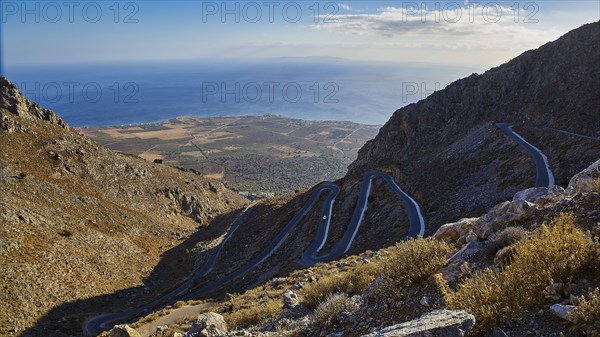 Serpentine road winds through a dry mountainous landscape down to the sea, Kallikratis, Kallikratis Gorge, Sfakia, West Crete, Crete, Greek Islands, Greece, Europe