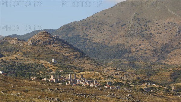 View of a quiet rural village surrounded by mountainous landscape under a clear blue sky, Flomochori, residential towers village, Mani Peninsula, Peloponnese, Greece, Europe