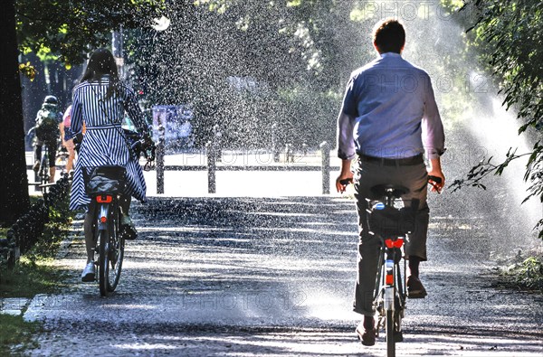 A cyclist cools down with a lawn sprinkler in Berlin's Tiergarten, 03/08/2022