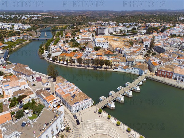 River with bridge through a Mediterranean-style town, recognisable by the red roofs and urban landscape, aerial view, Tavira, Faro, Algarve, Portugal, Europe