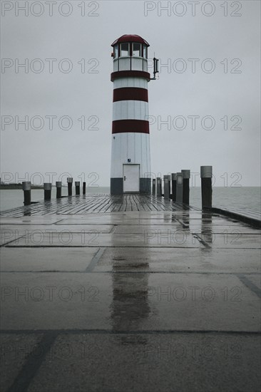 Lighthouse on a wooden jetty, surrounded by a rainy sky, Podersdorf, Burgenland, Austria, Europe