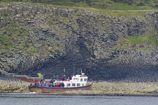 A boat loaded with people approaches the rocky coast, tourist boat, Hebrides Overture, Staffa Island, Inner Hebrides, Scotland, Great Britain