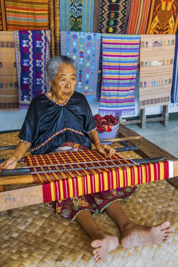 Traditional weaver, weaving, woman's work, working conditions, loom, textile, woman, trade, bazaar, authentic, fabric, fabric pattern, craft, handicraft, Asian, indigenous, tradition, traditional, marketplace, travel, tourism, culture, poverty, presentation, lifestyle, person, Muslim, Islam, Sasak, indigenous, indigenous people, cultural heritage, silk weaving, Sade village, Lombok, Indonesia, Asia