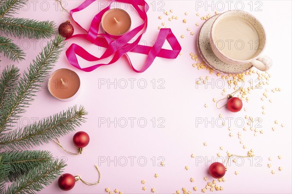 Christmas or New Year frame composition. Decorations, red balls, fir and spruce branches, cup of coffee, candles on a pink paper background. Top view, copy space, flat lay
