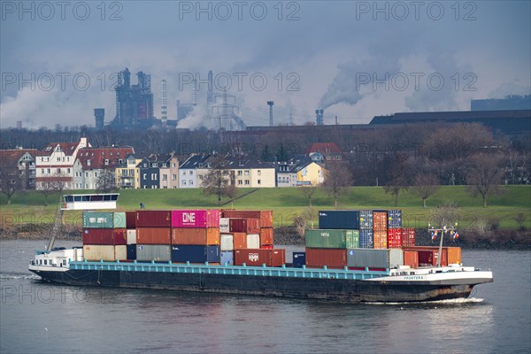 The river Rhine near Duisburg, houses on the Rhine dyke, Laar district, Thyssenkrupp Steel steelworks in Bruckhausen, cargo ship, Duisburg, North Rhine-Westphalia, Germany, Europe