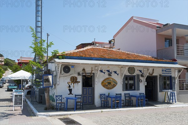 Rustic tavern on the corner with white facade, blue chairs and decorative elements surrounding, Sarti, Sithonia, Halkidiki, Halkidiki, Central Macedonia, Greece, Europe