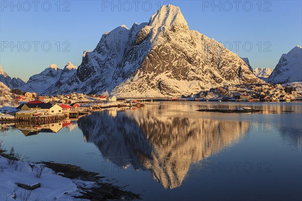 Snow-covered mountains reflected in fjord at sunrise, village, winter, Reine, Moskenesoya, Lofoten, Norway, Europe