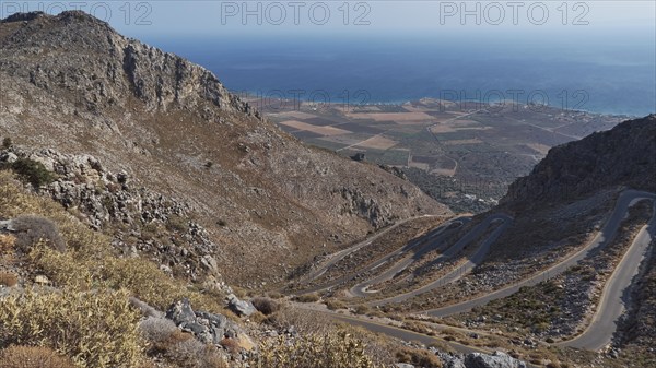 Panorama of a winding road that stretches through hilly terrain to the coast and the blue sea, Winding road along the Kallikratis Gorge, Lefka Ori, White Mountains, Mountain massif, West, Crete, Greece, Europe