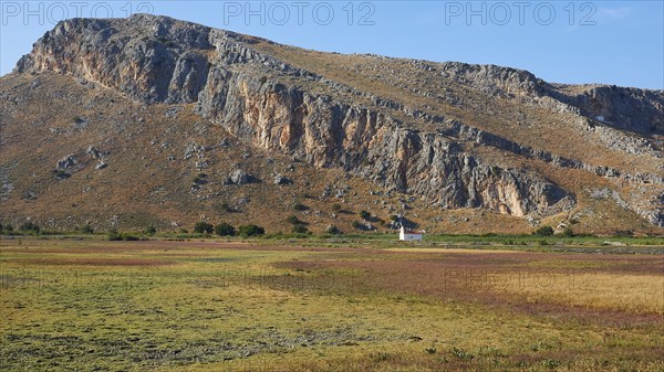 A small white chapel at the foot of a mountain surrounded by meadows, Strofilia biotope, wetlands, Kalogria, Peloponnese, Greece, Europe
