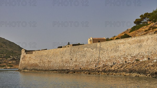 Long, old stone wall along the coastline, surrounded by a hill and calm sea, Venetian Sea Fortress, Leper Island, Spinalonga, Elounda Bay, Mirabello Bay, East Crete, Crete, Greek Islands, Greece, Europe
