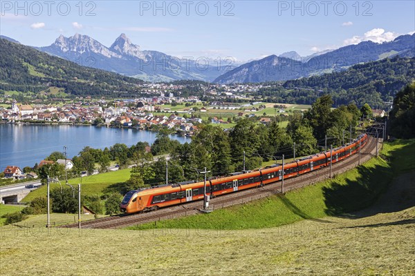Railway passenger train of the type Stadler Flirt of the Südostbahn on the mountain Großer Mythen at Lake Zug in the Alps in Arth, Switzerland, Europe