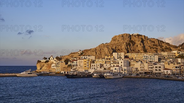 A coastal town with buildings and boats in the harbour under a rocky hill, Pigadia, town and harbour, Pigadia Bay, main town, Karpathos, Dodecanese, Greek Islands, Greece, Europe