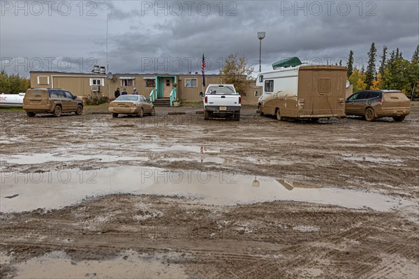 Dirty cars and muddy car park in front of pub, adventure tourism, Dalton Highway, Alaska, USA, North America