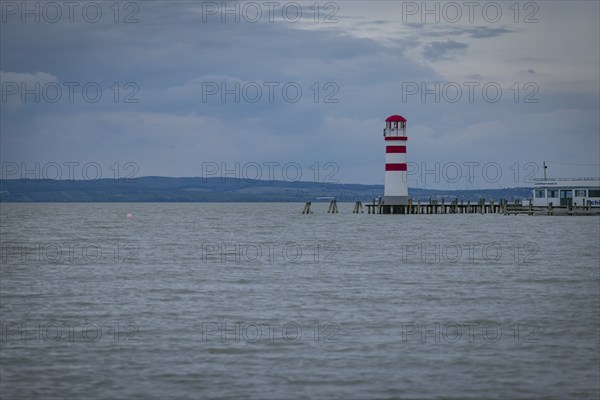 Red and white lighthouse stands on a calm lake under a cloudy sky, Podersdorf, Burgenland, Austria, Europe