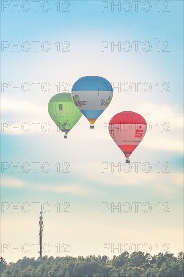Three hot air balloons flying near an antenna tower on a calm day, Calw, Black Forest, Germany, Europe
